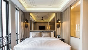 Ein großes Bett mit Holz-Kopfstück, einem Deckenventilator und einem an der Wand montierten Fernseher.