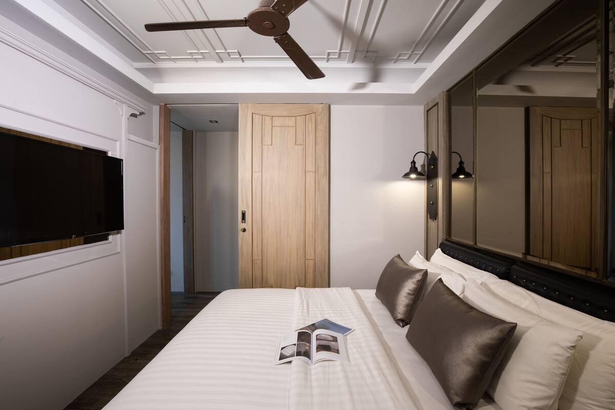 Ein Schlafzimmer mit Bett, Deckenventilator, Fernseher und Spiegel.