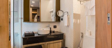 A modern bathroom with a black countertop sink, a mirror, a toilet, and a shower area.