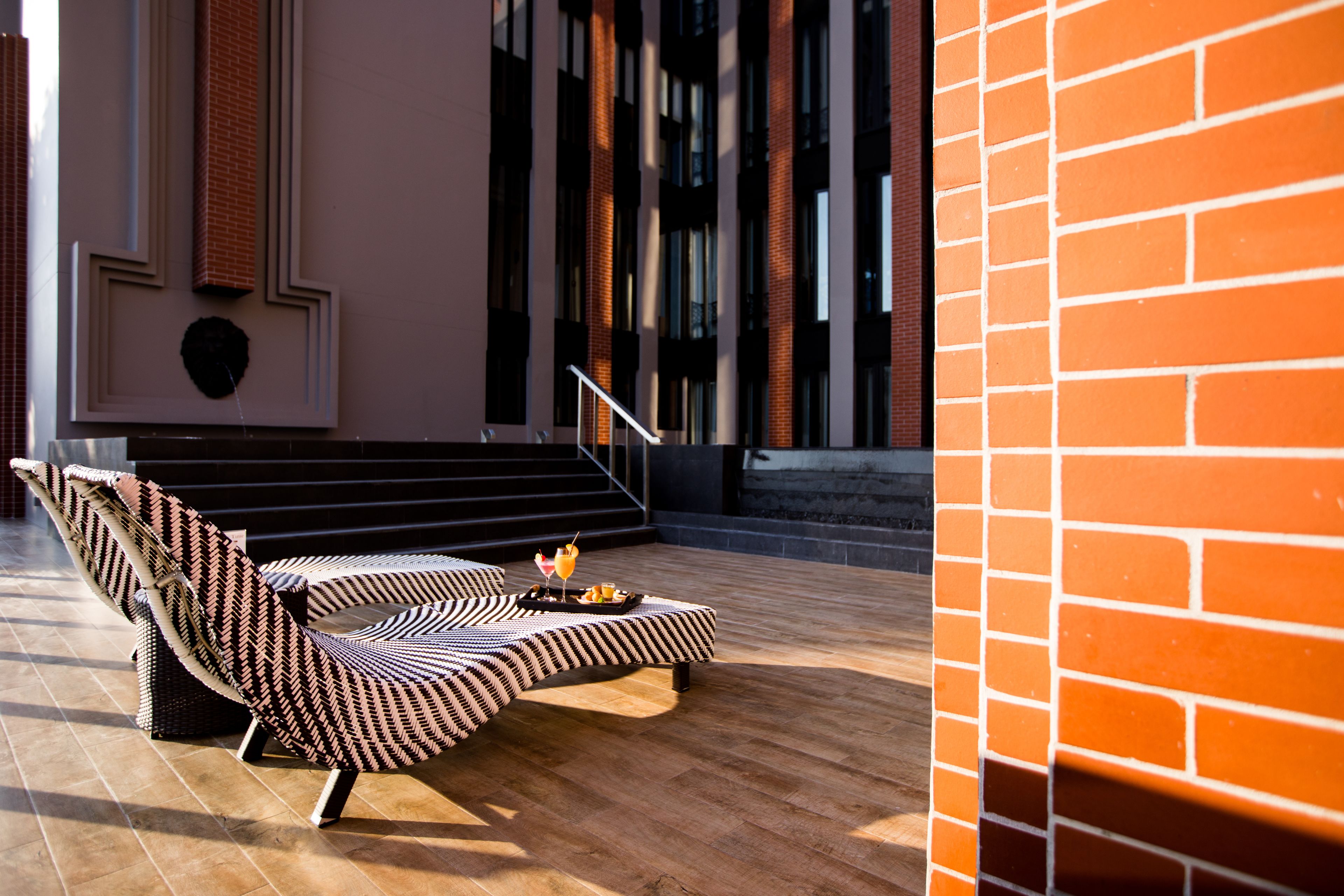 Un espace détente moderne avec un canapé à motifs et un plateau contenant une boisson et des en-cas.