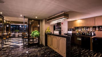 Zona de bar con suelo de mármol negro, armarios de madera y una variedad de botellas de licor.