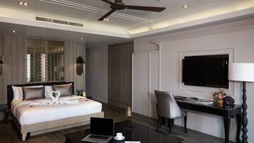Quarto de hotel moderno com uma cama grande, uma escrivaninha com um laptop, uma cadeira, uma TV e um ventilador de teto.
