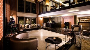 Eine geräumige Lobby mit hoher Decke, einem Weihnachtsbaum und einer Sitzecke mit Sofas und Sesseln.