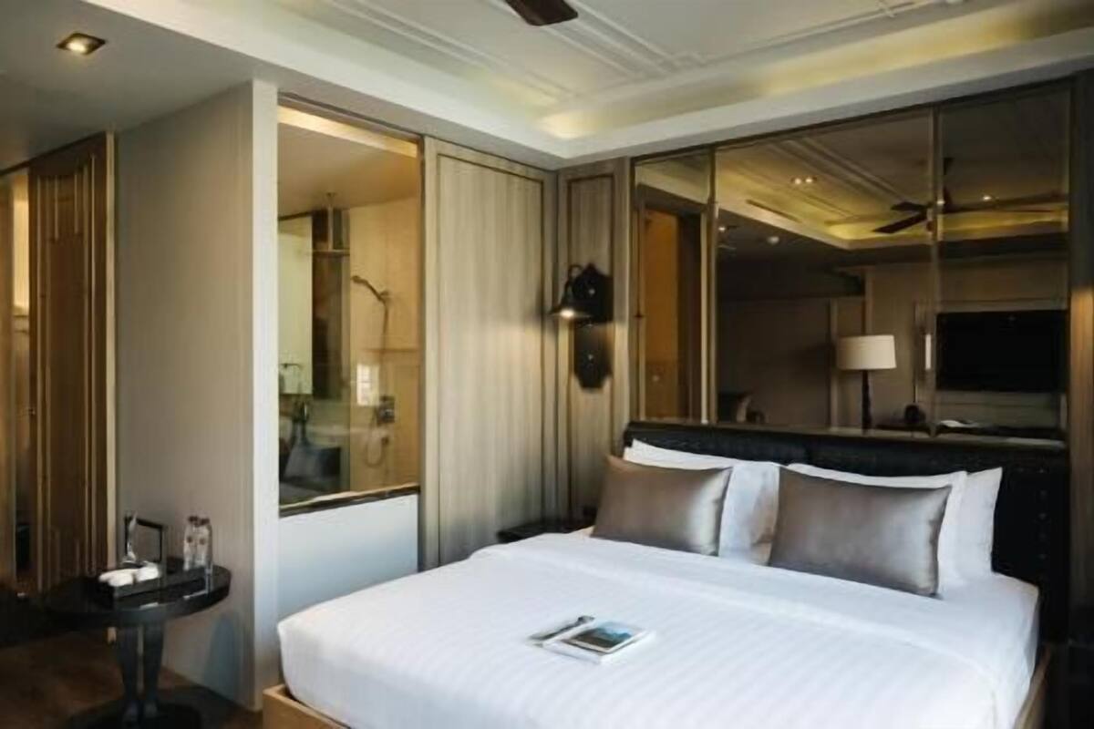 Ein Hotelzimmer mit Bett, Nachttisch, Spiegel und Fernseher.