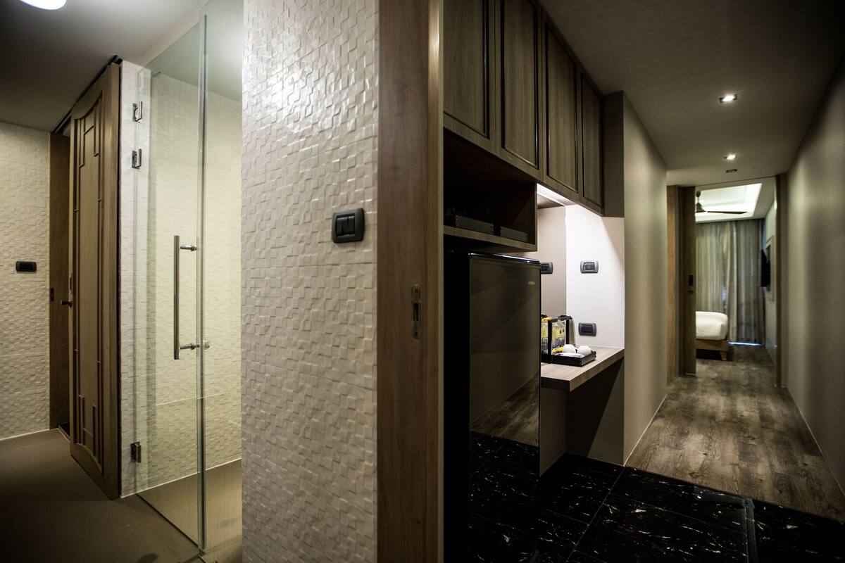Ein Hotelkorridor mit einer Glasdusche, einem Holzkabinett und einem Marmorboden.