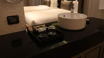 Un baño de hotel con encimera negra, un lavamanos blanco y dos vasos de vidrio sobre una bandeja.