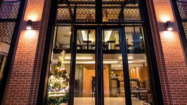 Ein modernes Gebäude mit Glastür, einem Weihnachtsbaum und einer Ziegelaußenwand.