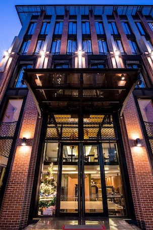 A modern building with a glass entrance, a Christmas tree, and a brick facade.