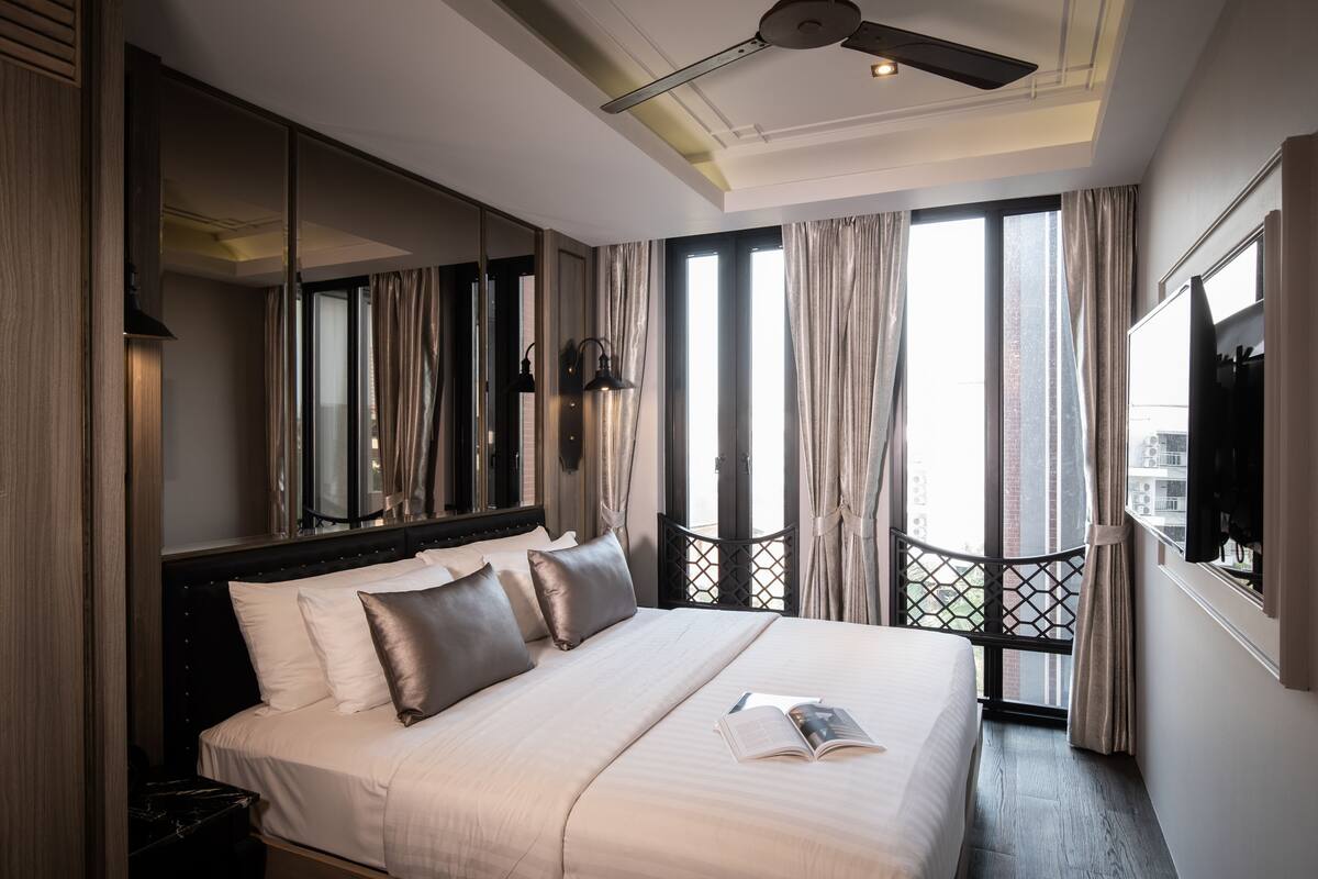 Ein Hotelzimmer mit einem großen Bett, einem Deckenventilator, einem Balkon mit Blick und einem großen Spiegel.