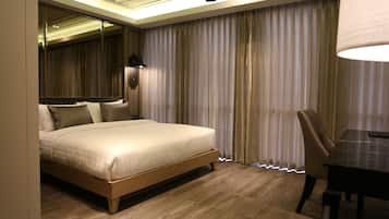 A modern hotel room with a large bed, a dining table, and a view through sheer curtains.