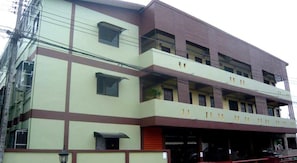 A multi-story building with a flat roof, large windows, and a red and beige color scheme. - Jansupar Court (Chiang Rai)