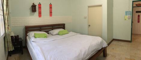 A bedroom with a bed, pillows, a nightstand, an air conditioner, and a door.