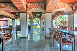 A covered outdoor dining area with brick arches, wooden benches, and tables. - Palm Beach Resort (Pranburi)