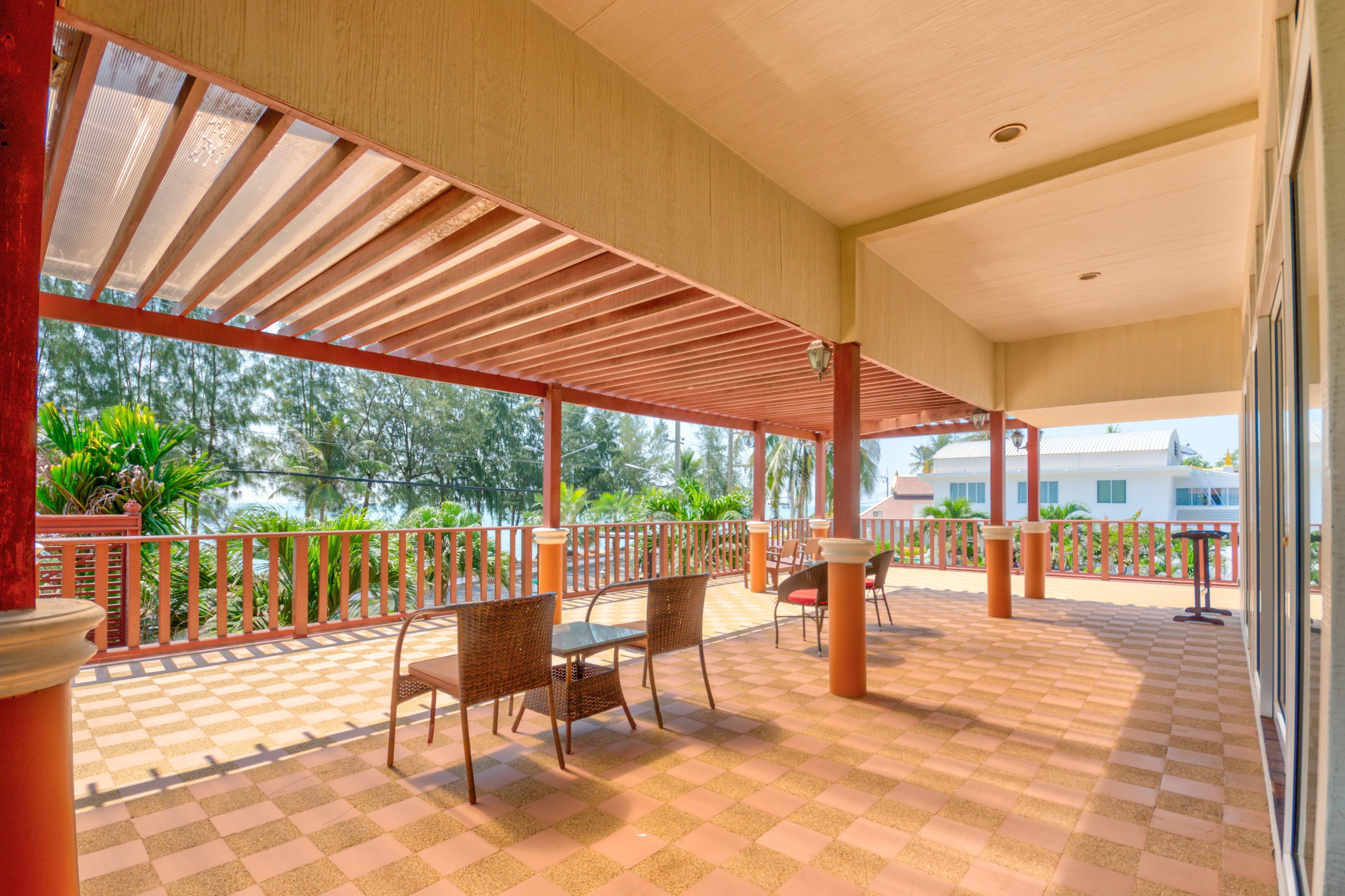 A covered outdoor seating area with checkered flooring, metal railings, and wicker chairs.
