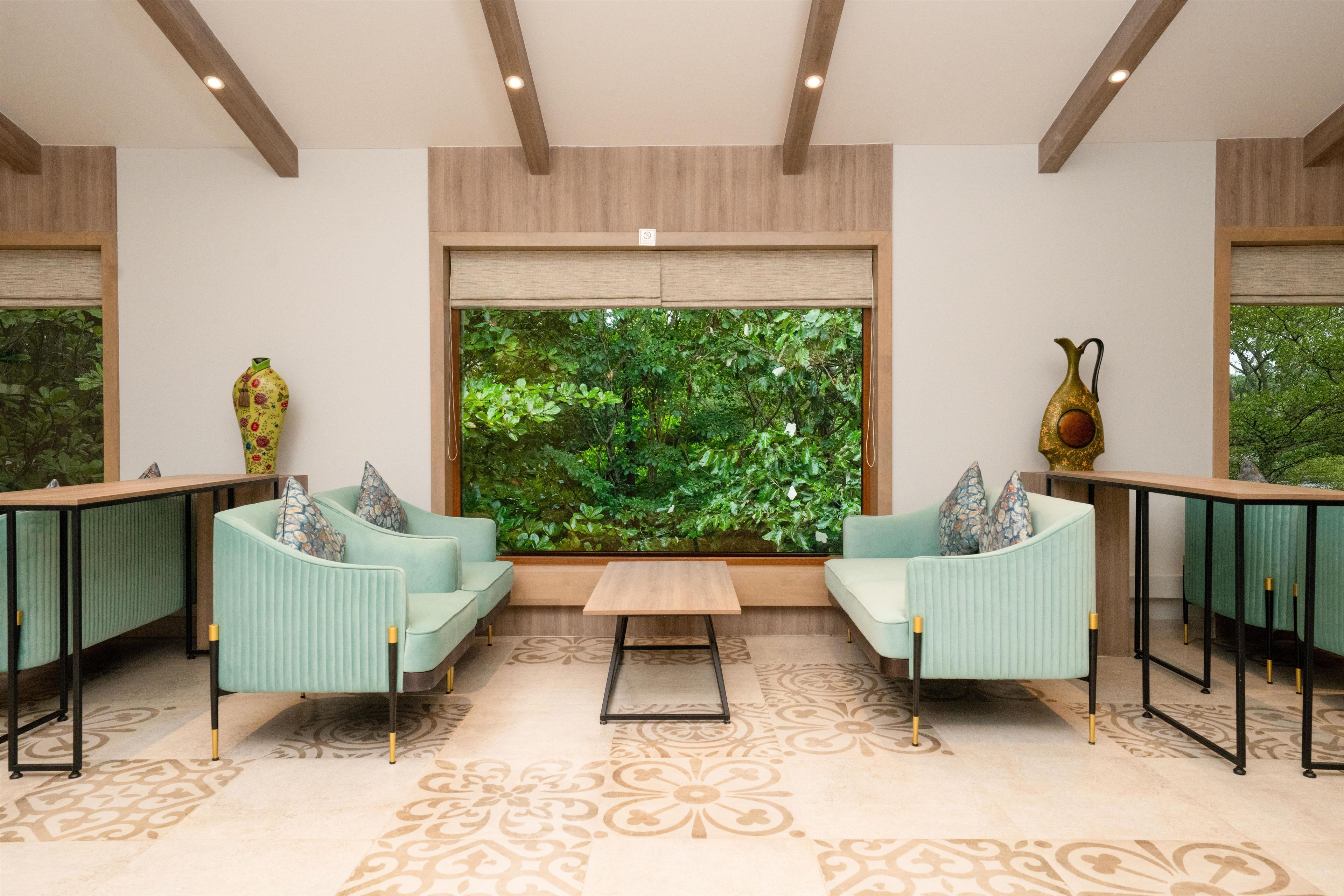A modern interior with two sofas facing a large window overlooking a lush garden.