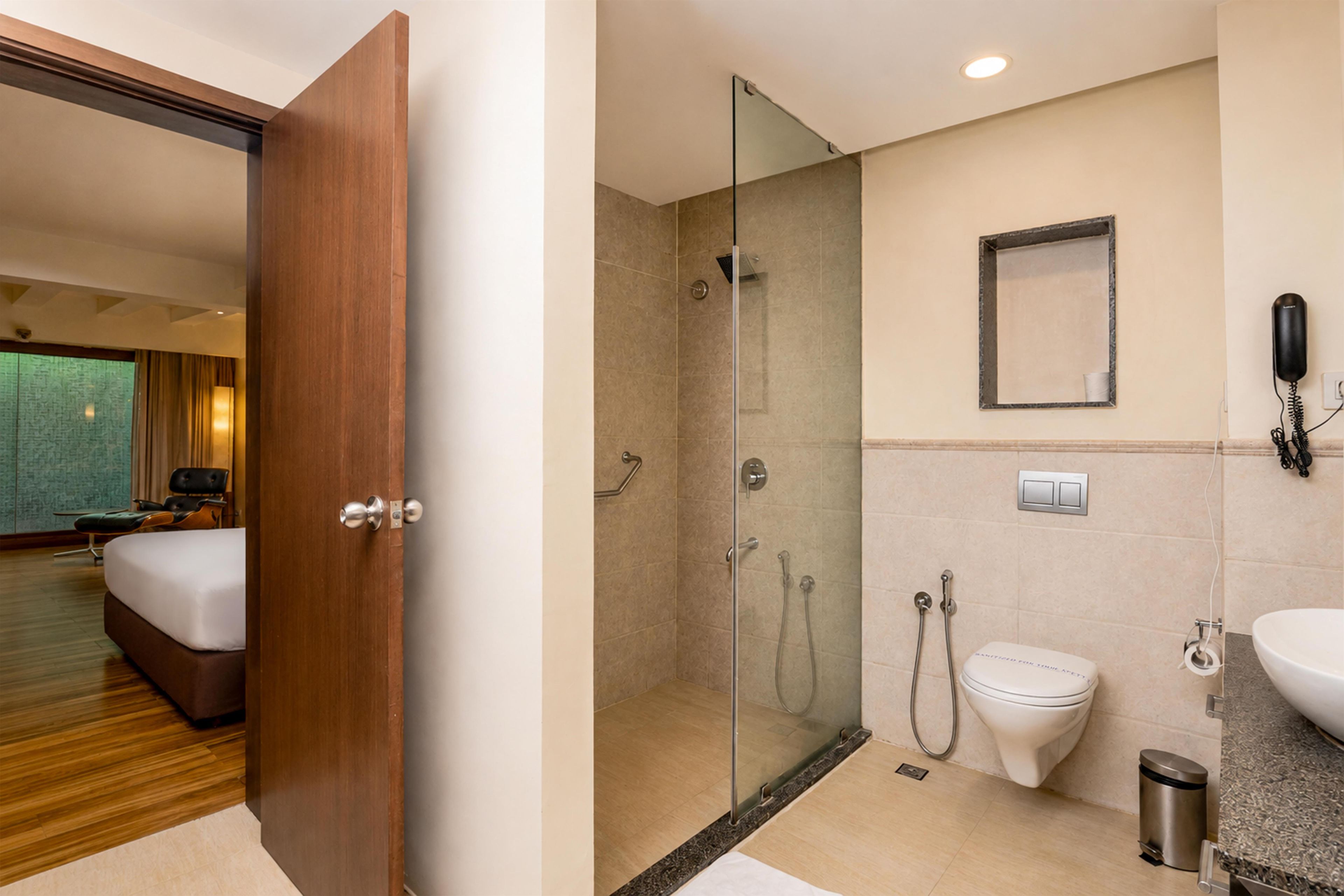 A hotel bathroom with a glass-enclosed shower, a toilet, a sink, and a telephone.