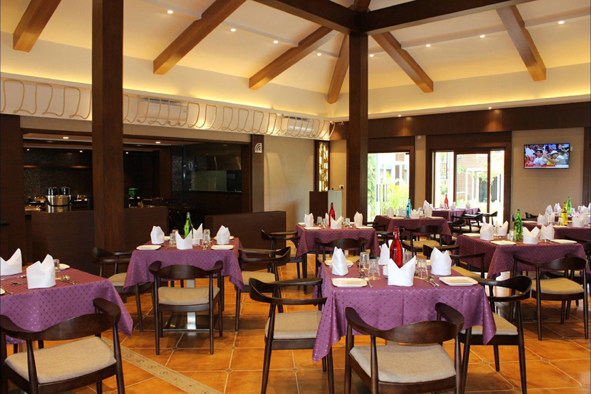 Un restaurante con varias mesas dispuestas para comer, con manteles morados y sillas de madera.