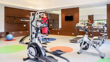 Une salle de sport équipée de vélos d’appartement, de machines elliptiques et d’un rameur.