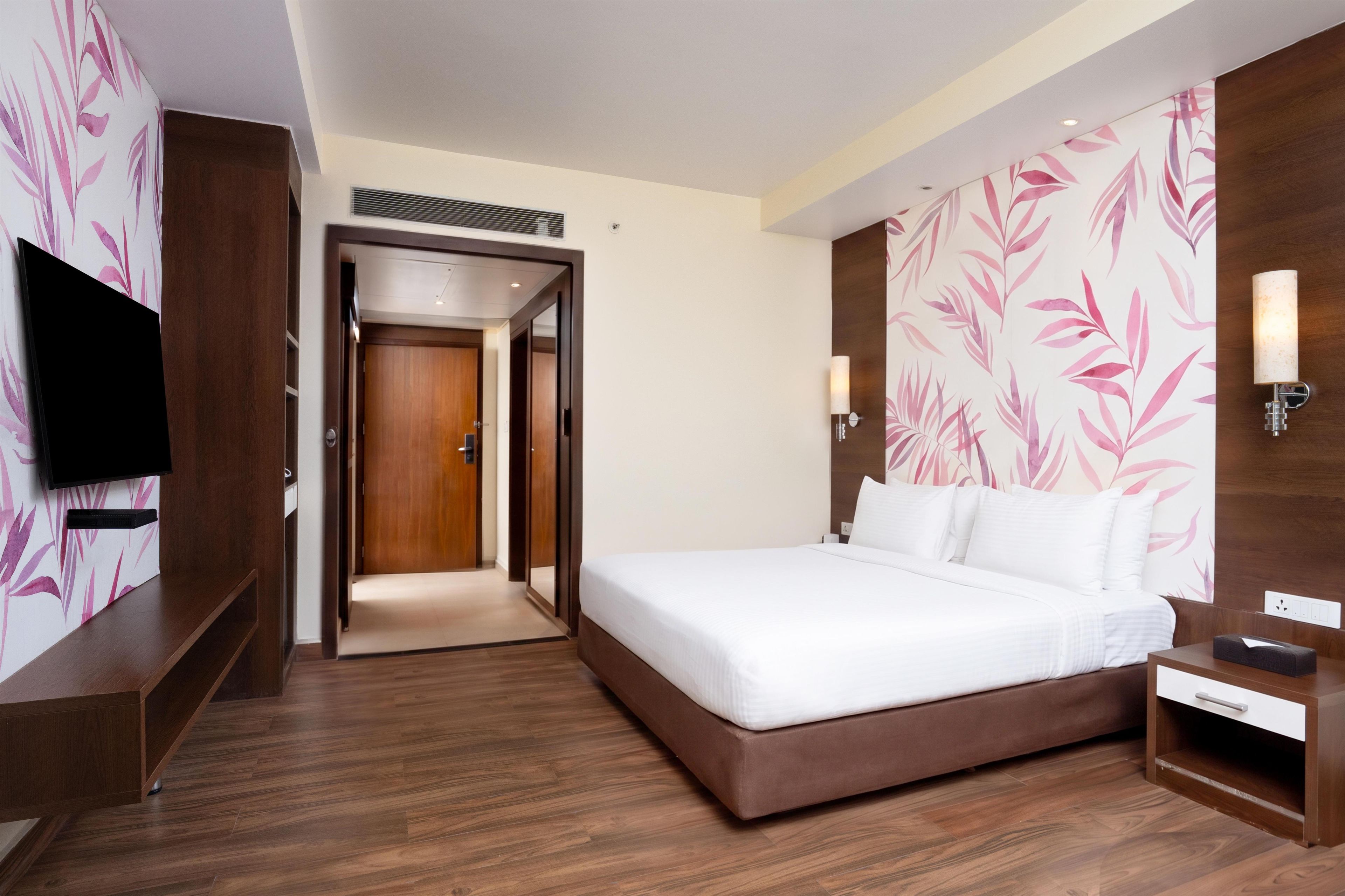 A hotel room with a bed, a TV, a bedside table, and a nightstand.