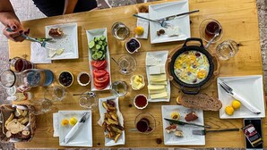 A wooden table with various breakfast items including eggs, bread, cheese, and fruits. - Merih Hotel (Bodrum)