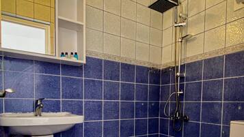 Un baño con lavamanos blanco, azulejos azules, ducha e inodoro.