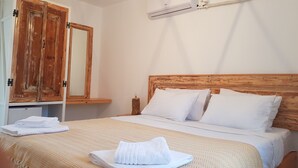 A hotel room with a wooden wardrobe, a bed with white linens, and a wall-mounted air conditioner. - Merih Hotel (Bodrum)