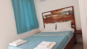 A single bed with a wooden headboard, white pillows, and a blue bedspread.