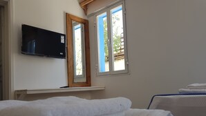 A hotel room with a bed, a TV mounted on the wall, and a window with a view of the outside. - Merih Hotel (Bodrum)
