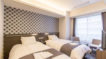 A hotel room with two beds, a TV, a desk, and a window with curtains.