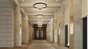 A modern hallway with a checkered floor, recessed lighting, and a central elevator. - Hotel M’s Plus Shijo - Omiya (Kyoto)