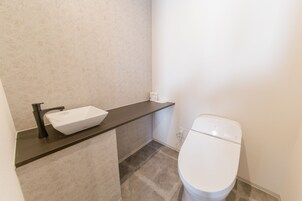 Une salle de bain avec un lavabo blanc, un robinet noir et des toilettes blanches.
