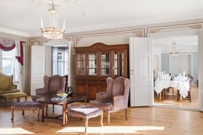 A spacious room with a wooden dining table set for a meal, surrounded by ornate chairs and a large wooden cabinet with glass doors. - Kongsvinger Castle Hotel & Resort (Kongsvinger)