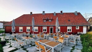 A red building with a tiled roof and multiple windows. There are outdoor tables and chairs arranged in rows. - Kongsvinger Castle Hotel & Resort (Kongsvinger)