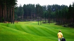 A golf course with a person walking with a golf bag. - Kongsvinger Castle Hotel & Resort (Kongsvinger)