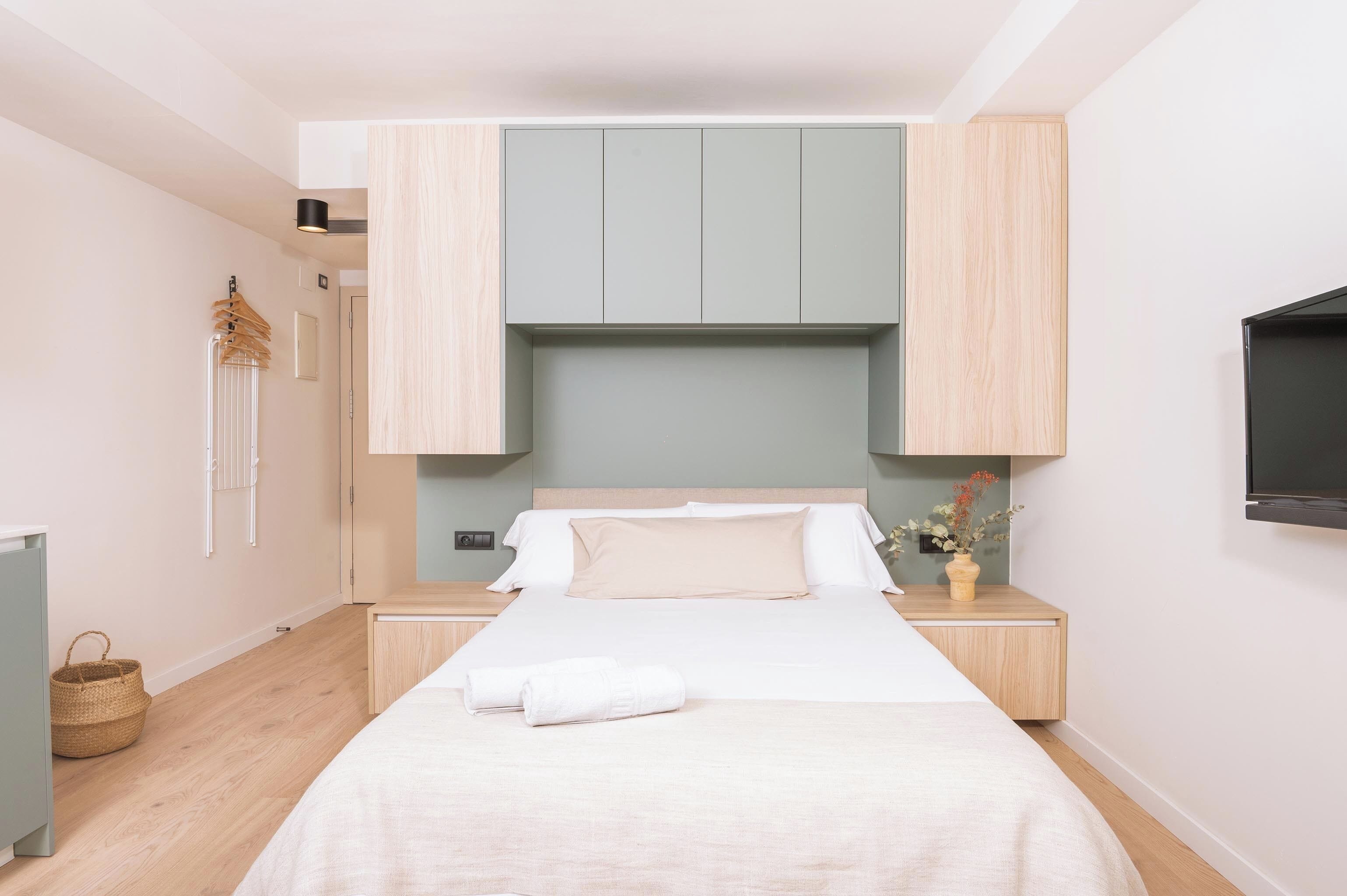 Un dormitorio con cama, televisor, armario y mesita de noche.