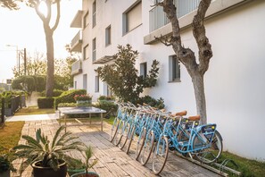 A row of bicycles parked against a building, a table with chairs, and potted plants. - Apartaments Marfina (Castelldefels)