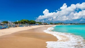 Una playa con aguas turquesas cristalinas, una orilla arenosa y varios barcos.