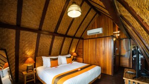 Un dormitorio acogedor con piso de madera, una cama grande, una mesita de noche, una lámpara y un espejo.