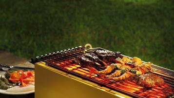 Una parrilla con diferentes carnes y verduras asándose al aire libre.