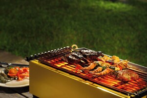 Una parrilla con diferentes carnes y verduras asándose al aire libre.