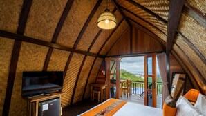 Una habitación con una cama, un televisor sobre un mueble de madera y un balcón con vistas.