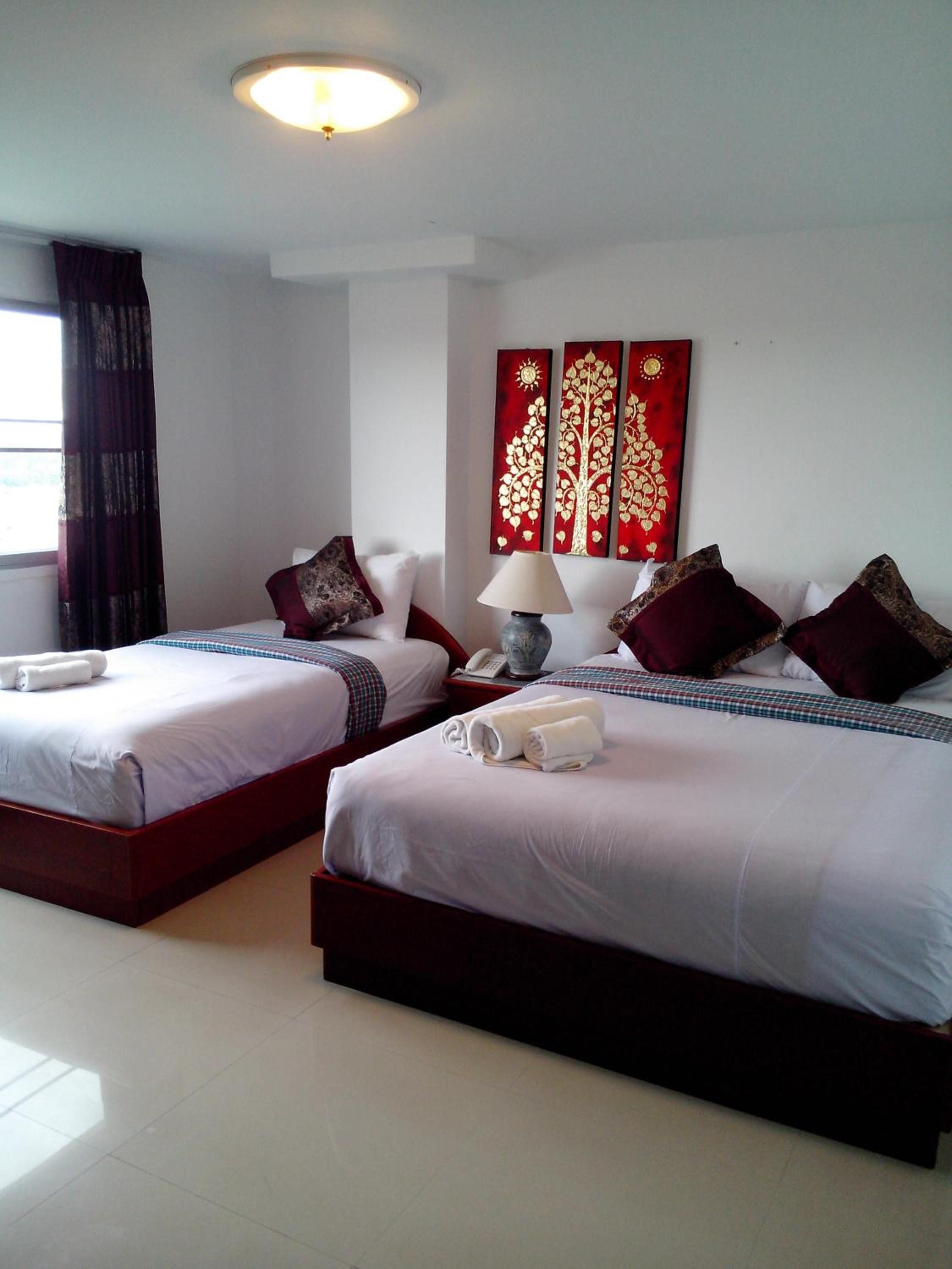 Habitación de hotel con dos camas, una lámpara, un teléfono y una obra de arte en la pared.