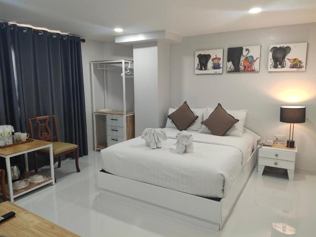 Una habitació d'hotel amb un llit gran, una taula de nit amb una làmpada, un armari i una taula petita amb una cadira.