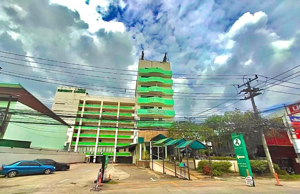 A multi-story building with a green and white facade, a parking area, and a sign indicating a service area.
