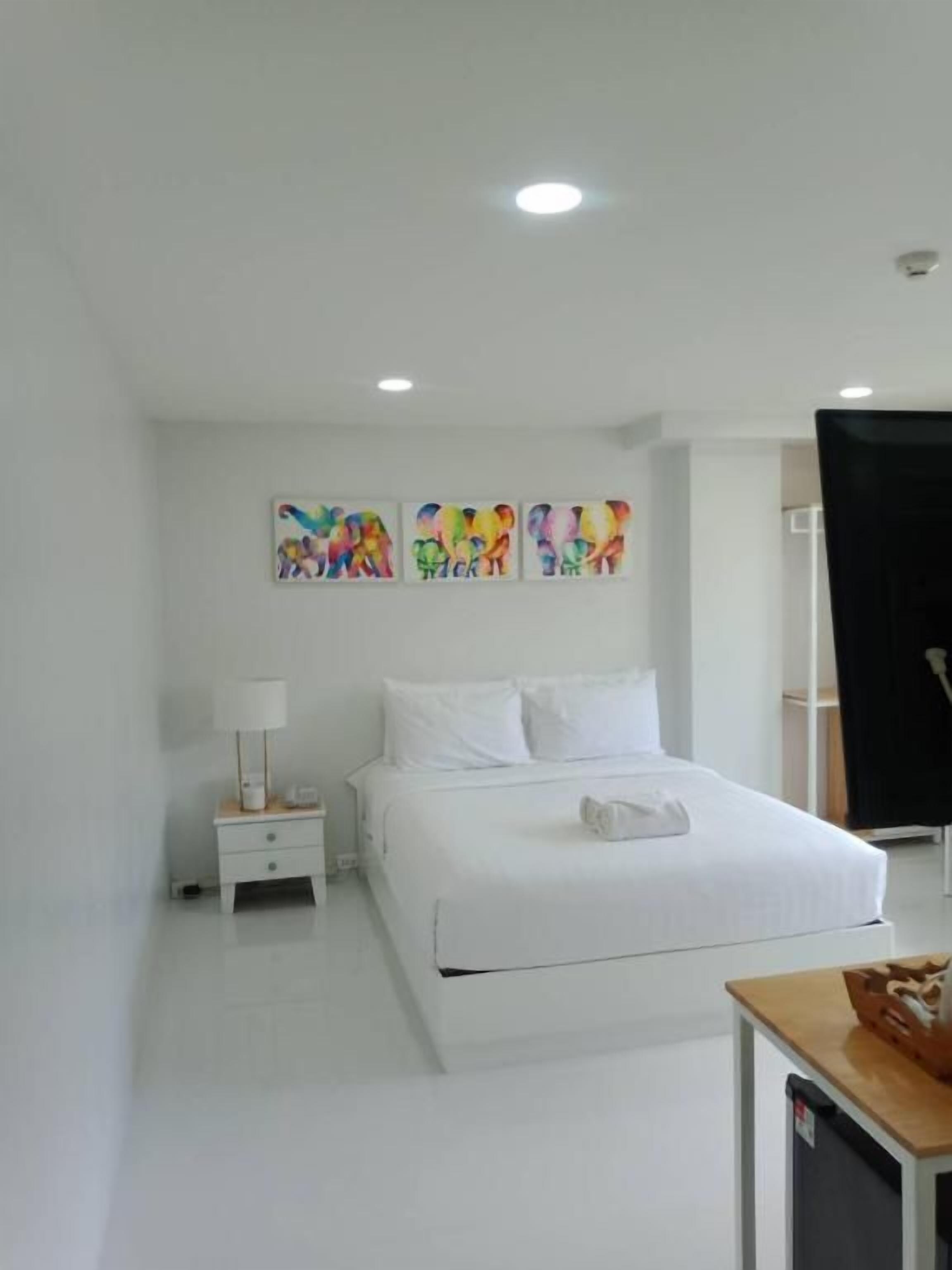 A hotel room with a bed, a nightstand, a lamp, and artwork on the wall.
