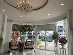 A lobby with a chandelier, seating area, and large windows with a view of the outside. - Regent Lodge Lampang (Lampang)