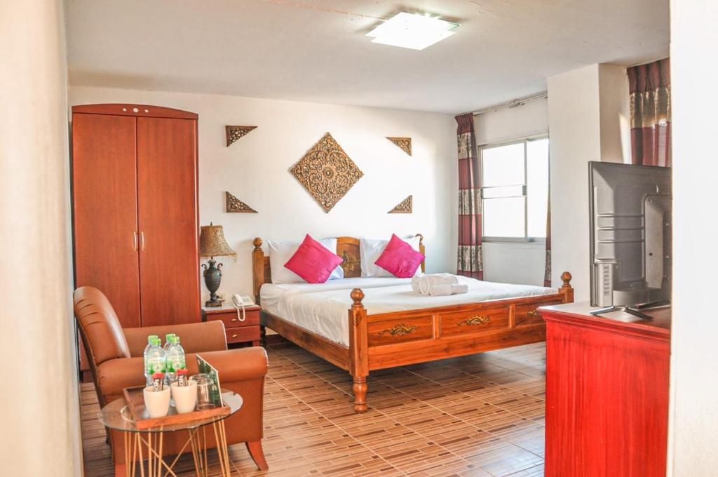 A bedroom with a wooden bed, a red cabinet, a television, and a small table with bottles.