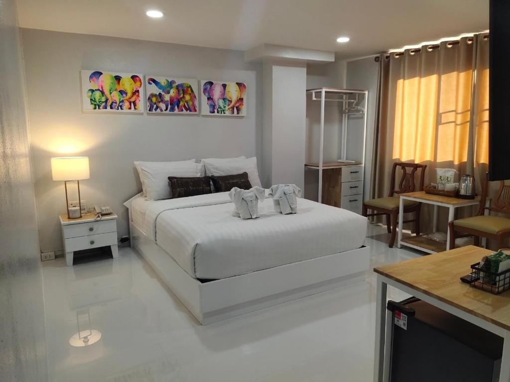 A modern bedroom with a large bed, bedside tables, a wardrobe, a desk, and a chair.