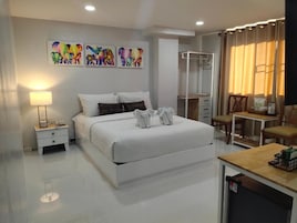 Un dormitorio moderno con una cama grande, mesitas de noche, un armario, un escritorio y una silla.