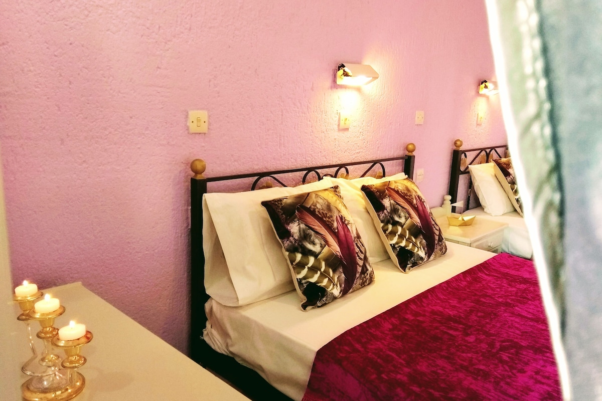 A bedroom with a bed, a nightstand, and a wall-mounted light.